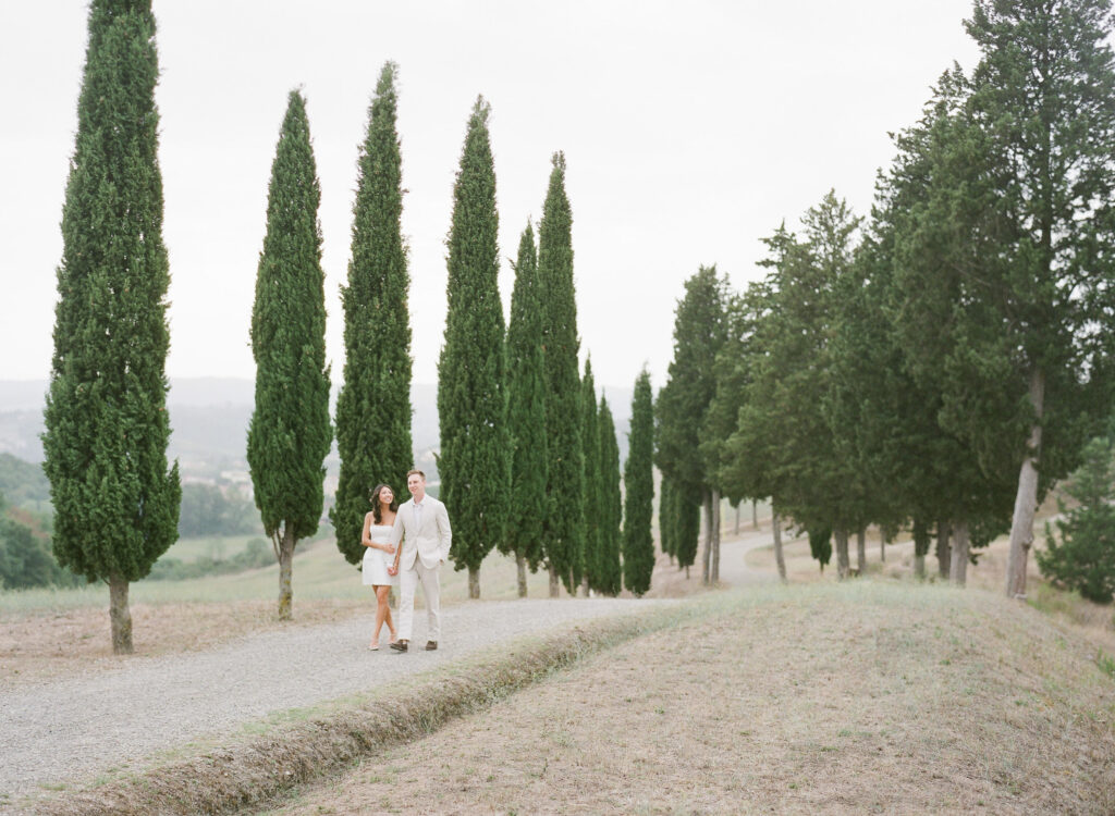 Walking through a lane of Cipress trees during an engagement session in Tuscany, photographed by European Wedding photographer Alexandra Vonk